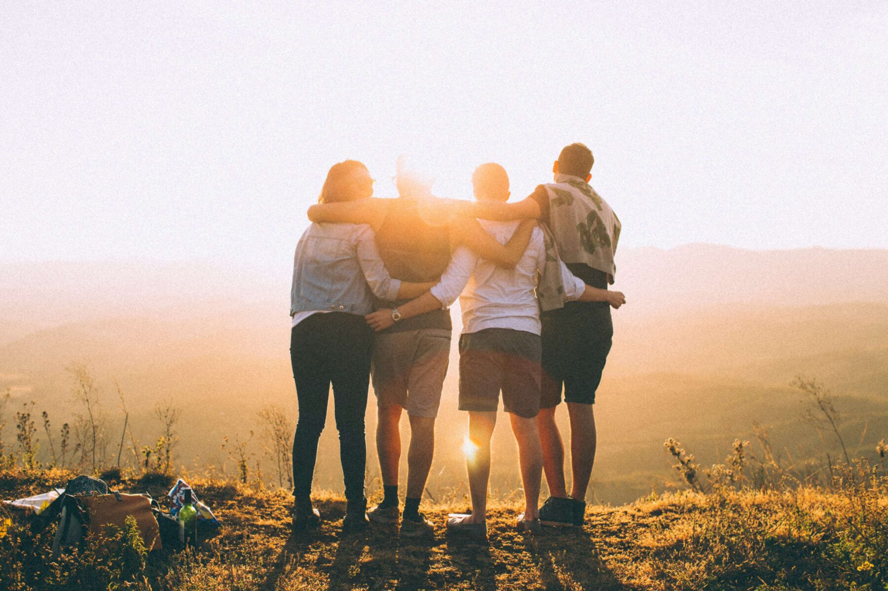 4 friends holding each other watching a sunset