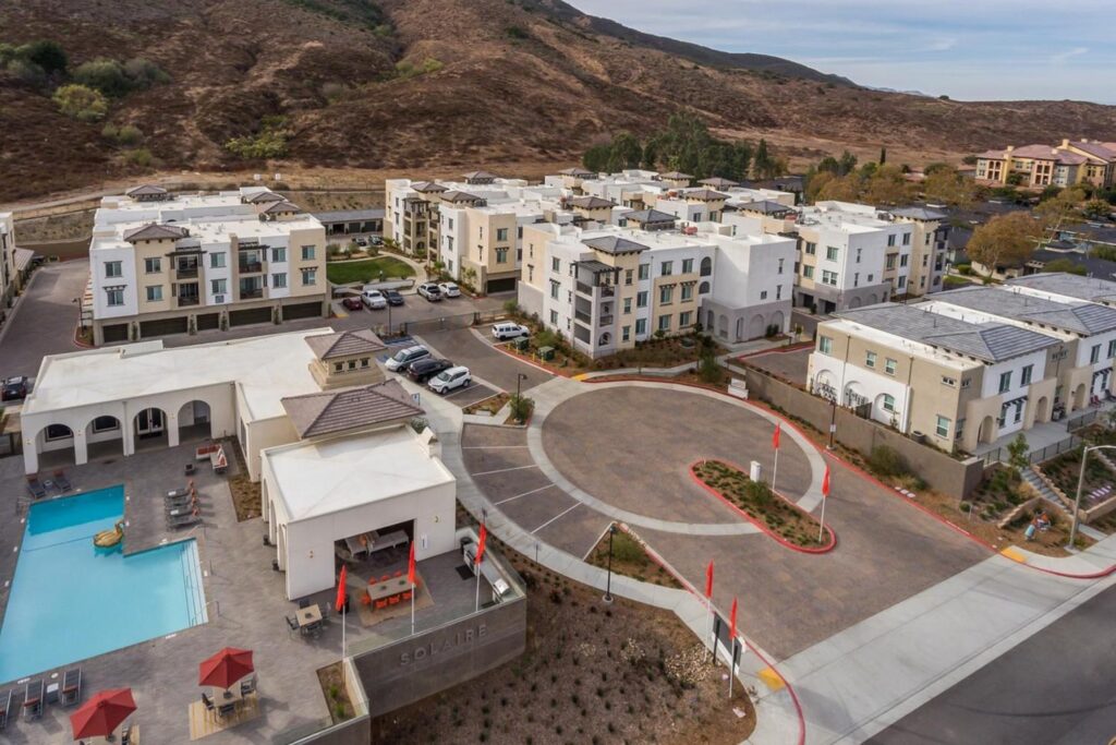 Top view of the apartment with swimming pool, parking area and a large mountain on the back.