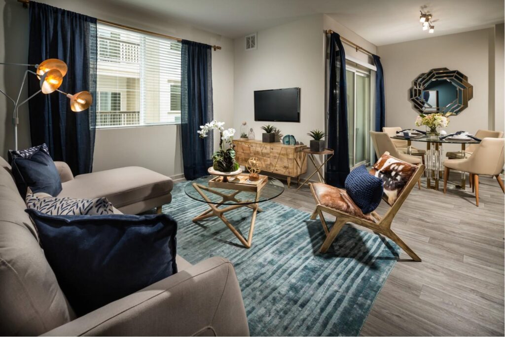 Living room with a wall mounted TV, couch and a tall lamp with lights turned on.