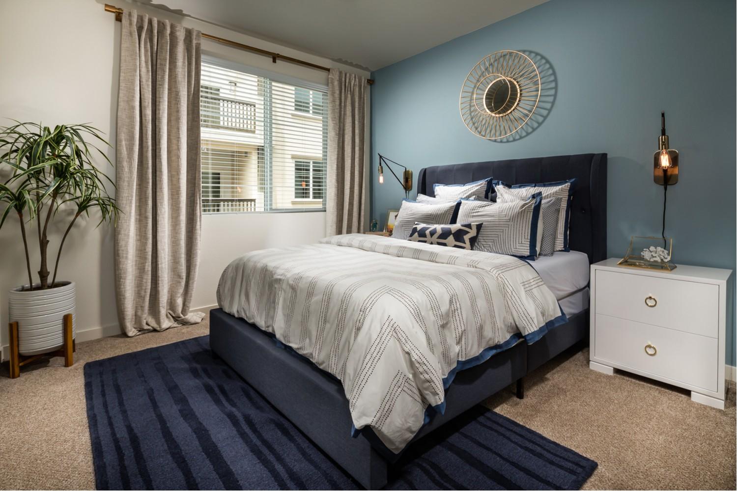 Bedroom with bluish bed, light grey comforted and pillows