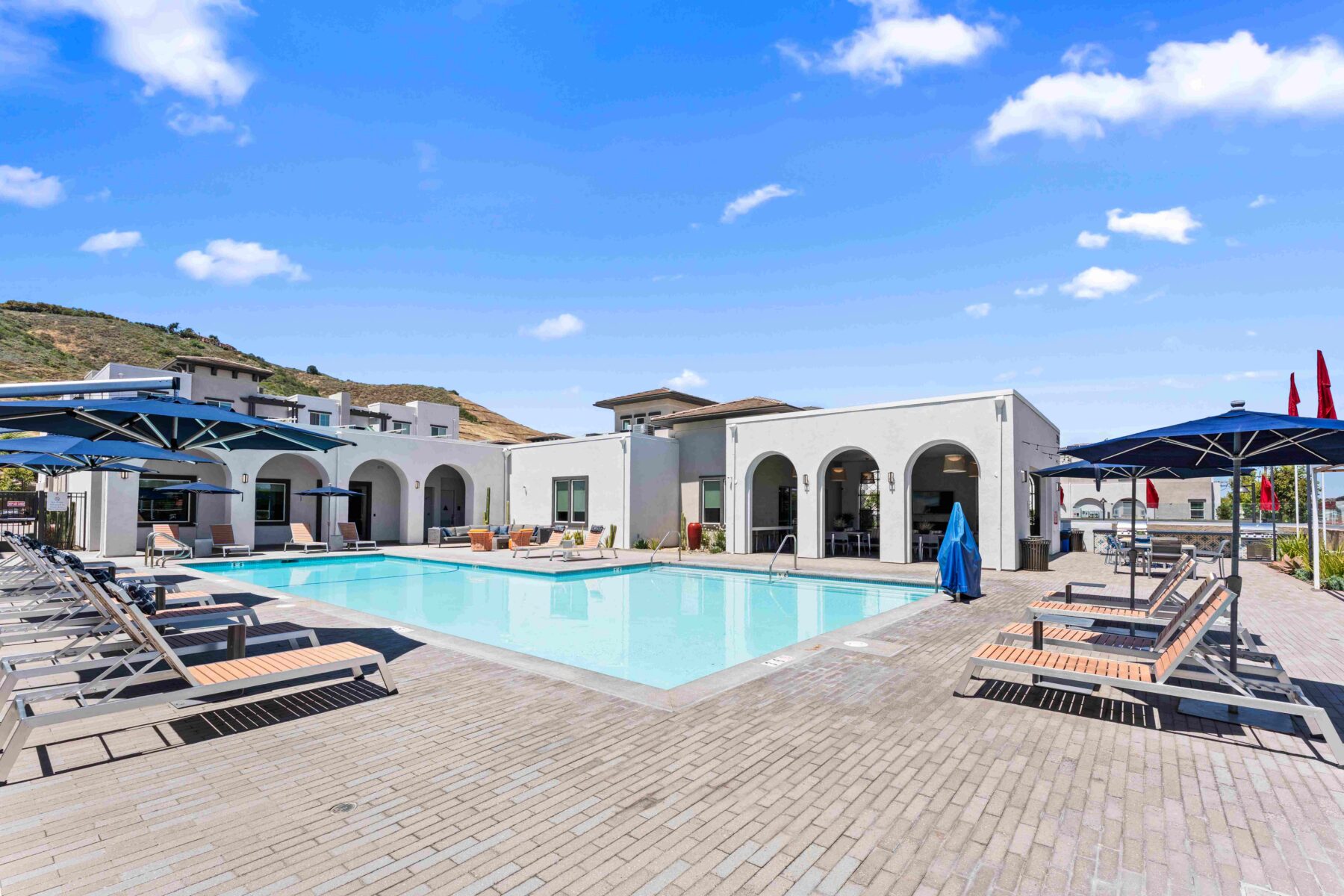 Pool with lounge chairs and umbrellas at Solaire luxury apartments in Temecula, CA.